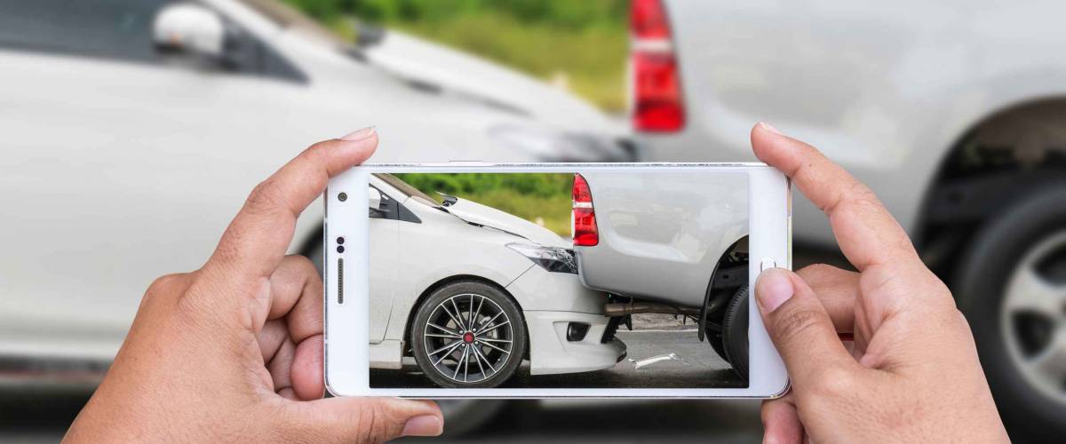 Close up hand of woman holding smartphone and take photo of car accident