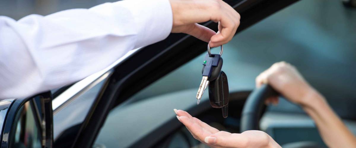 Close up of car dealer giving keys of a new car to woman