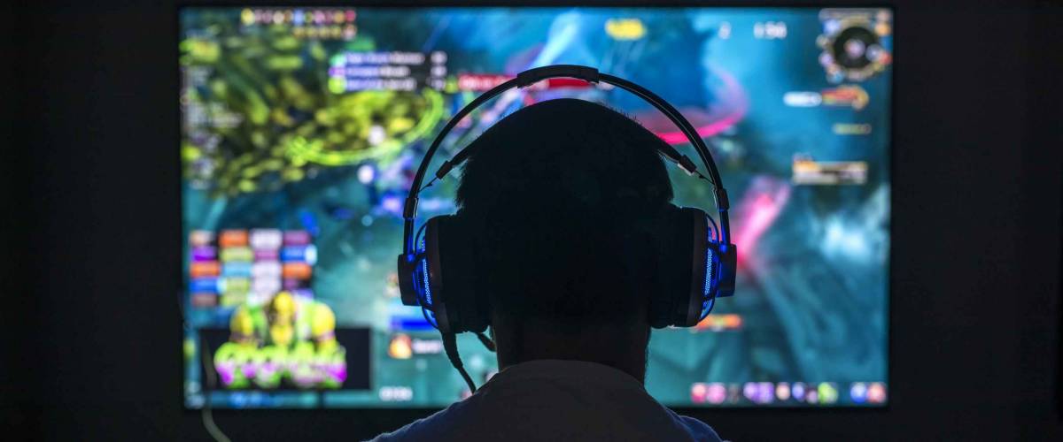 Young gamer playing video game wearing headset in the dark