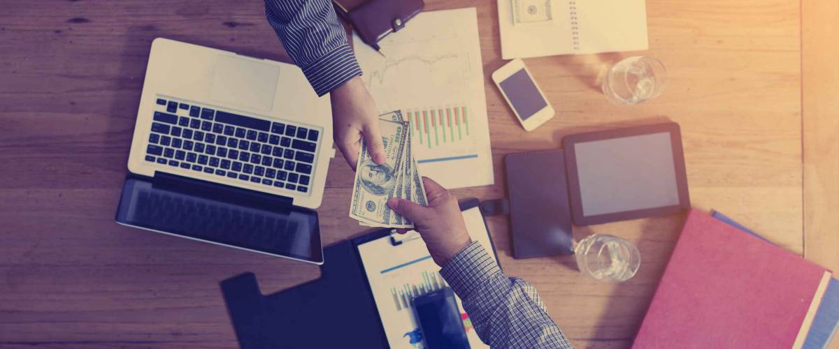 View from above of person passing money across a desk