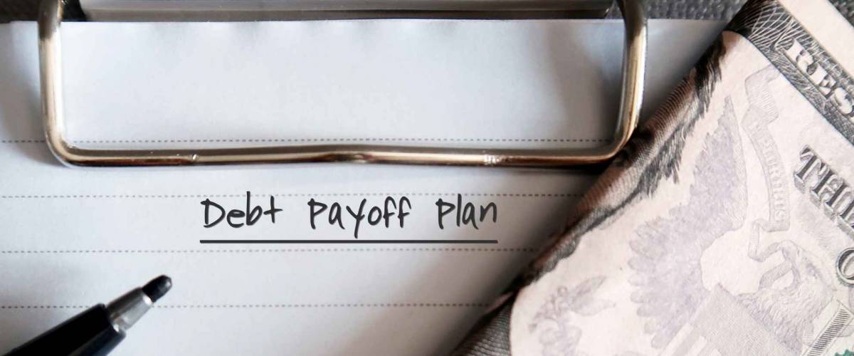 Black pen, cash dollar money on clipboard paper note with text written Debt Payoff Plan , concept of contribute money to pay off debt