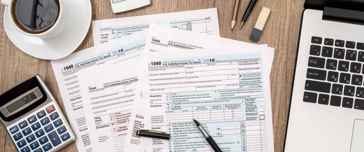 1040 tax form, laptop, glasses, coffee on desk