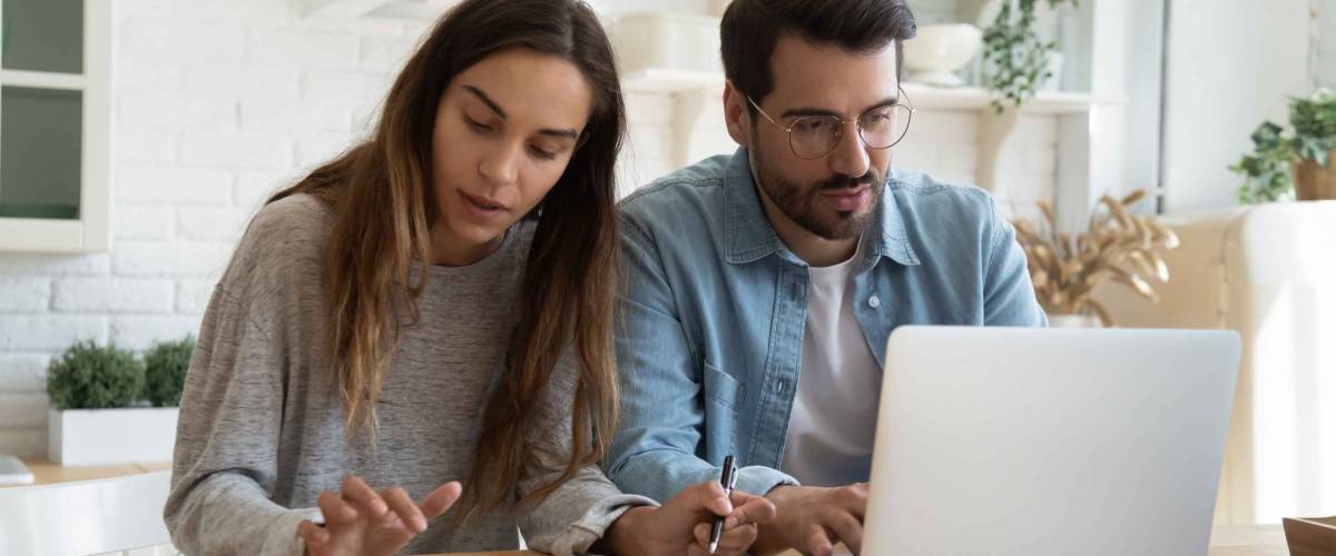 Serious man and woman calculating bills, using calculator and laptop, online banking services, family discussing and planning budget, focused wife and husband checking finances together