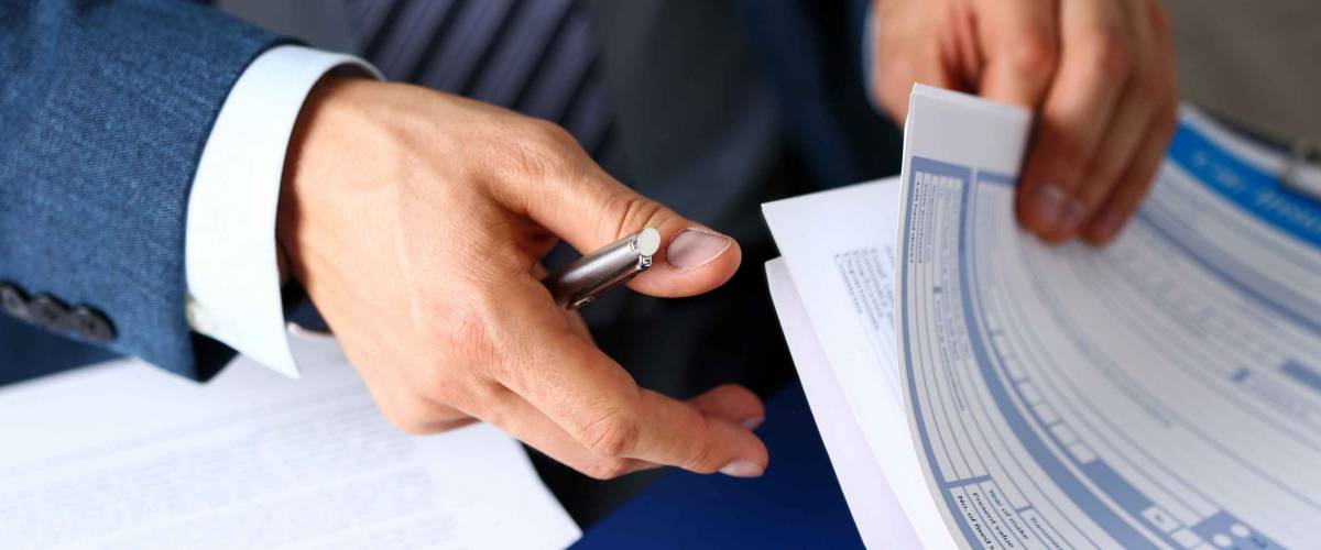 Close up of man's hands holding pen and insurance forms