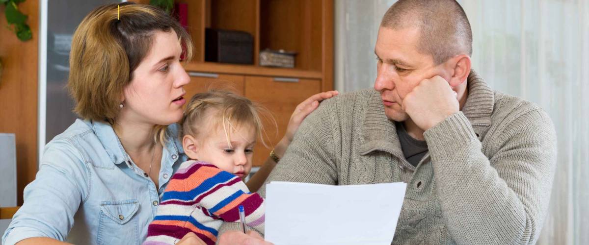 Worried family with child sitting with financial documents at home