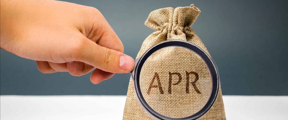 A hand points to a money bag with the word APR.
