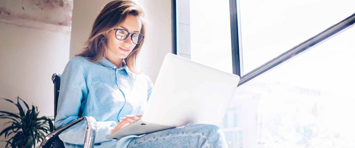 Woman using Laptop in huge Loft Studio to research refinance mortgage rates.