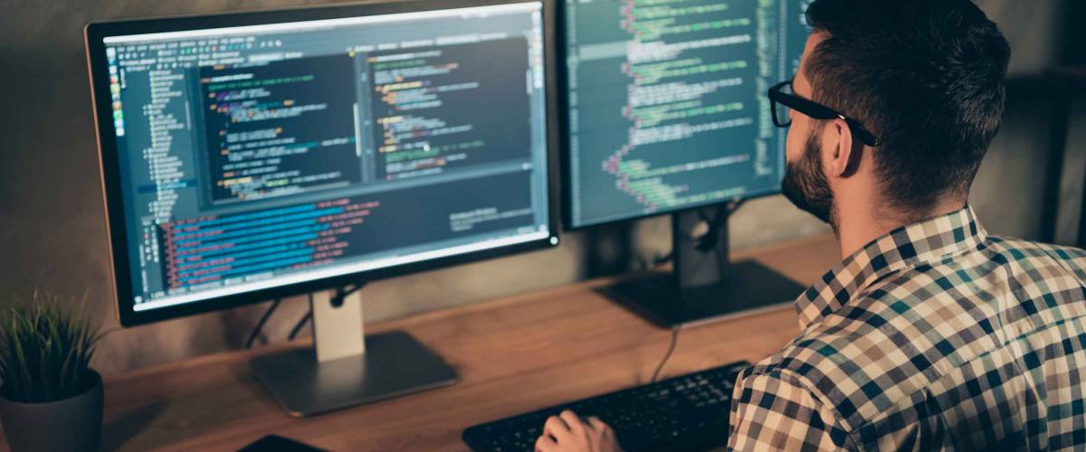 Profile side view of man working on two computer screens