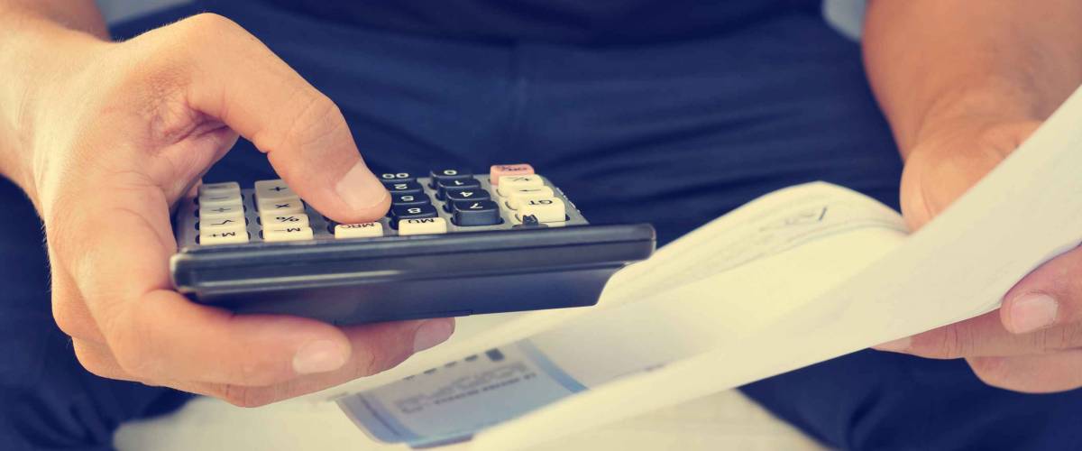 closeup of a young man checking a bill, a budget or a payroll with a calculator, filtered effect