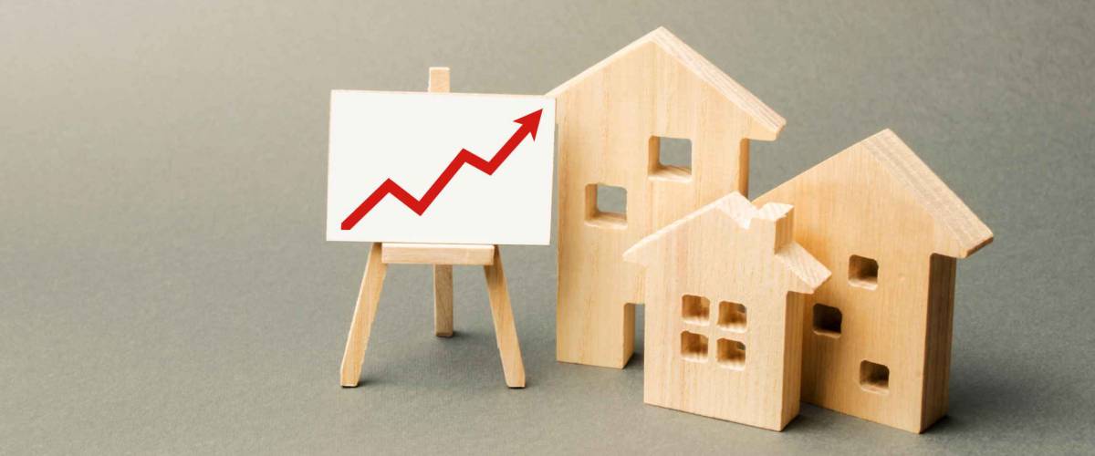 three wooden houses and a red up arrow on the sign. Real estate value increase. High rates of construction, high liquidity. Supply and demand. Rising prices for housing, building maintenance.