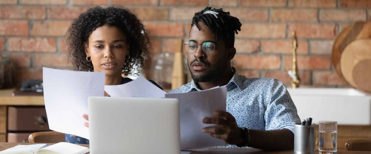 Focused Black couple researching mortgage offers.
