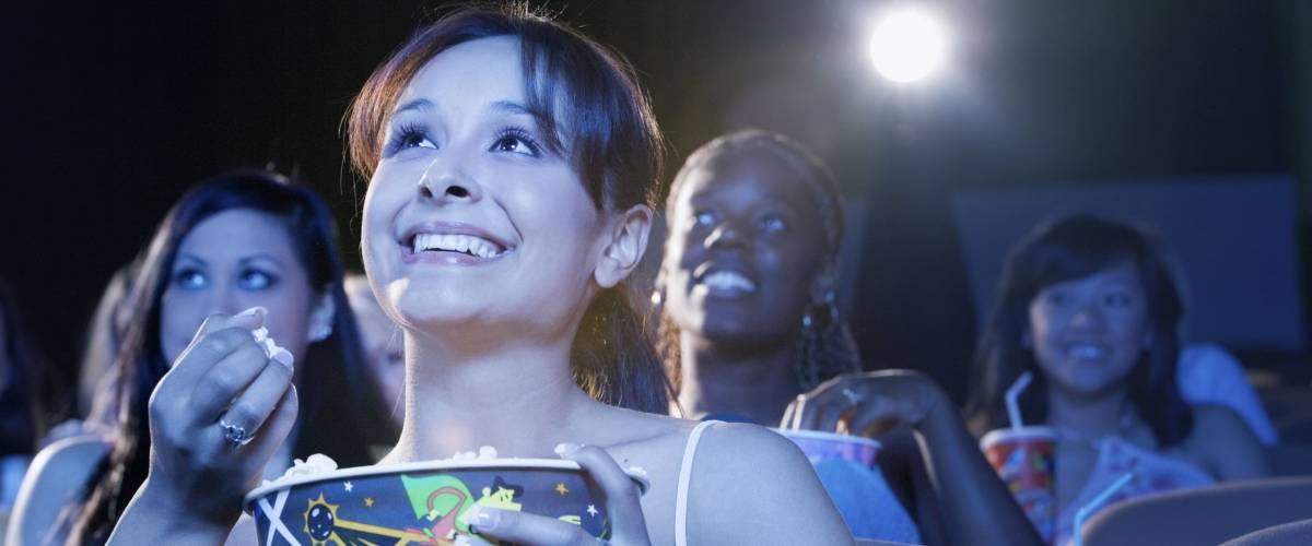 Smiling young women sitting and watching movie in the theatre
