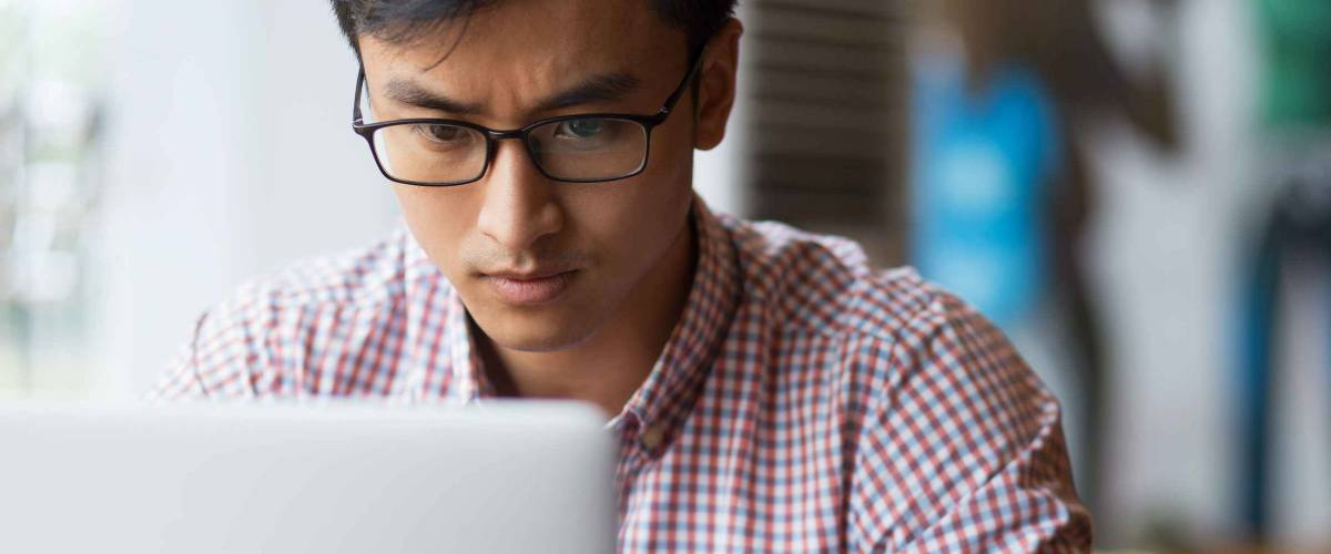 Concentrated young man typing on laptop in cafe