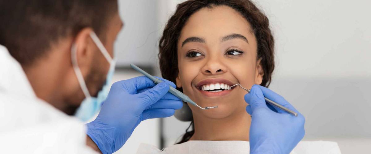 Pretty black lady in dentist chair looking at her doctor with smile, close up