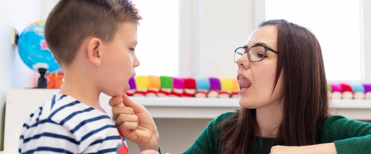Children speech therapy concept. Preschooler practicing correct pronunciation with a female speech therapist.