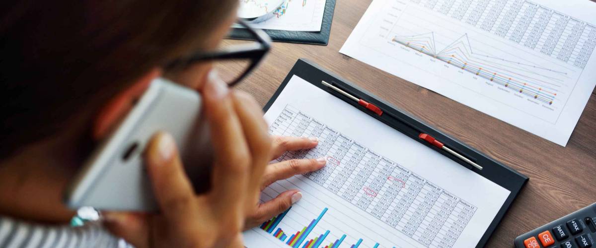 Business analysis - calculator, sheet, graphs (business report) and analyst hand, top view
