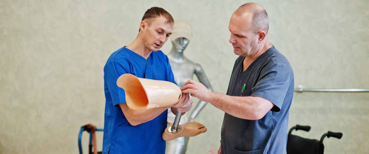 Two prosthetist man workers with prosthetic leg working in laboratory.