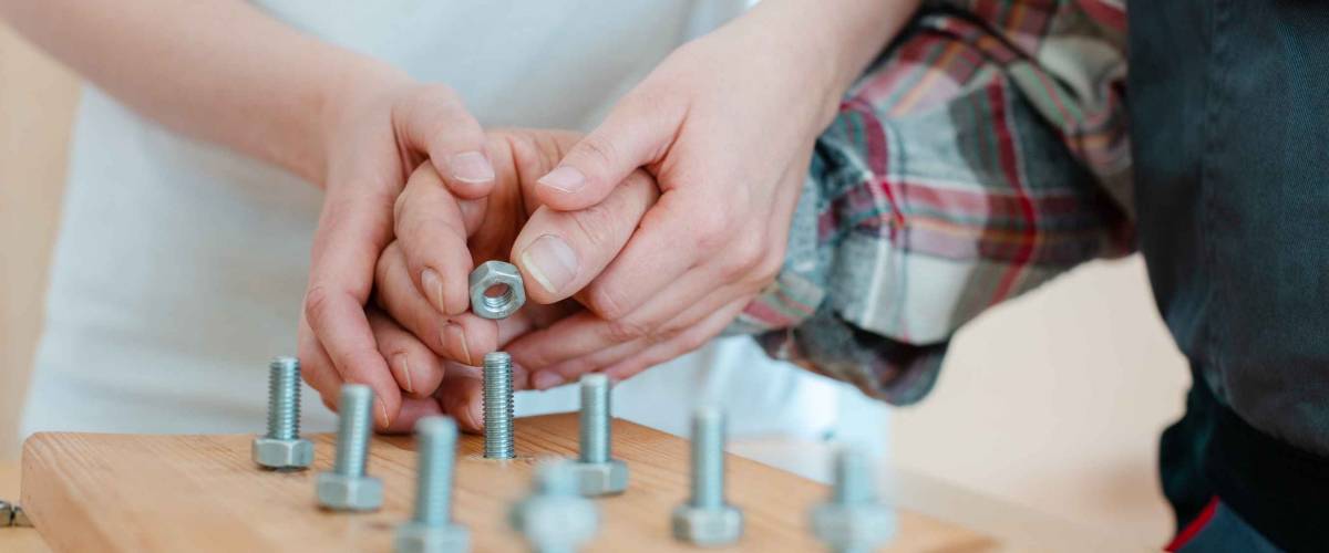 Closeup on hand of man in occupational therapy screwing nut on bolt