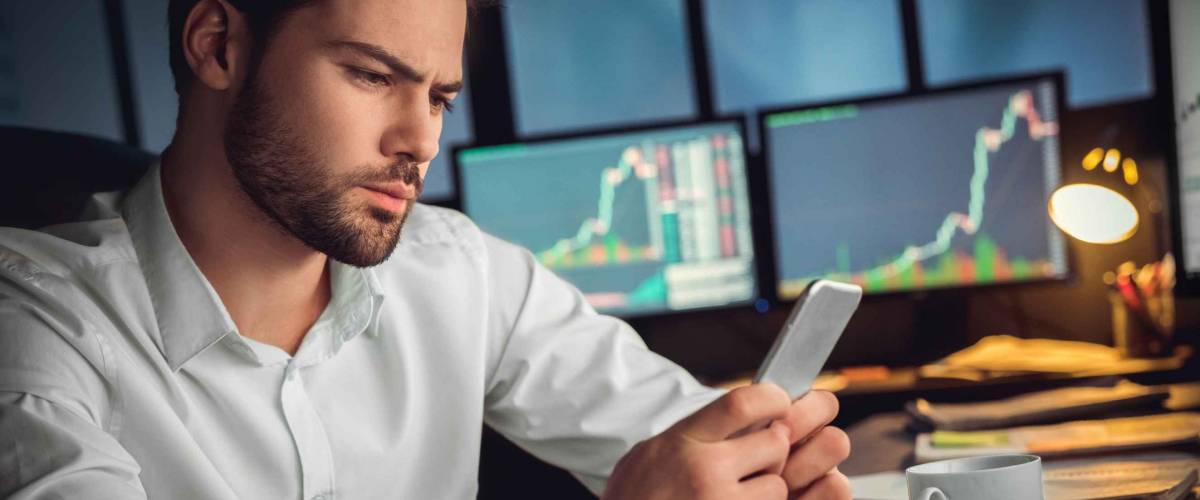 Serious trader using mobile phone app on smartphone for checking stocks.