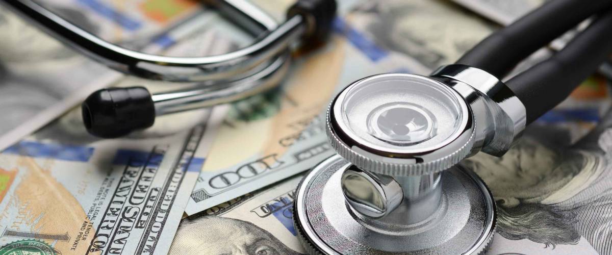 Medical stethoscope on heap of dollar bills. Health care or insurance costs concept. Finance banking audit analytics.