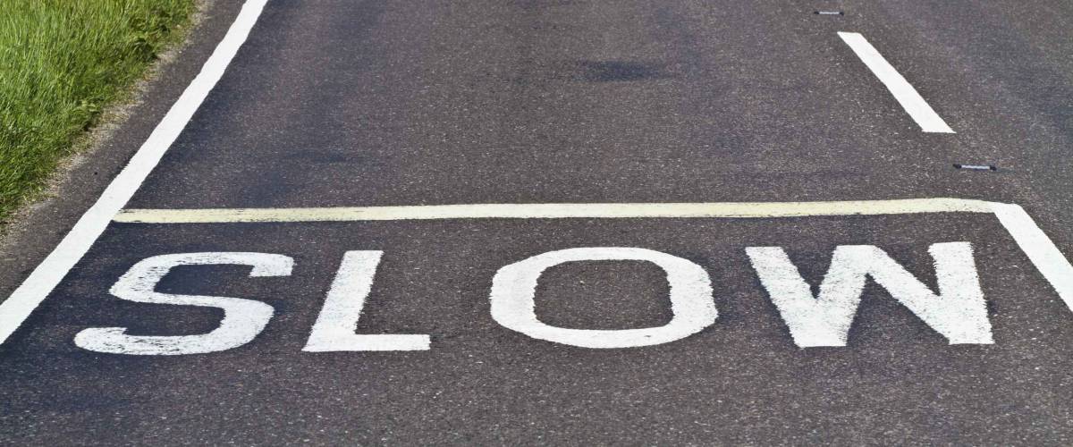 Three warning signs to slow down painted on a curving road