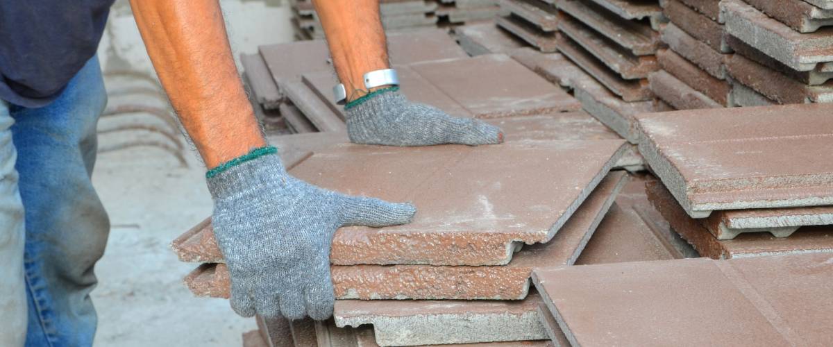 Workers were moving a lot of brown roof shingles to the roof to make a step towards the roof.