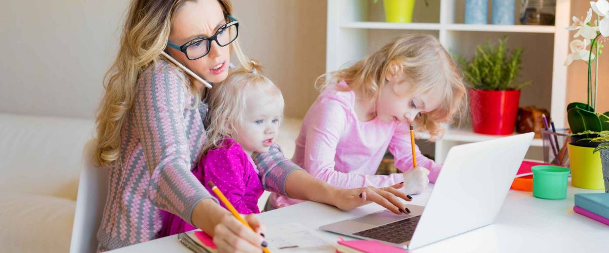 Busy woman trying to work on laptop and talking on the phone while with two little kids