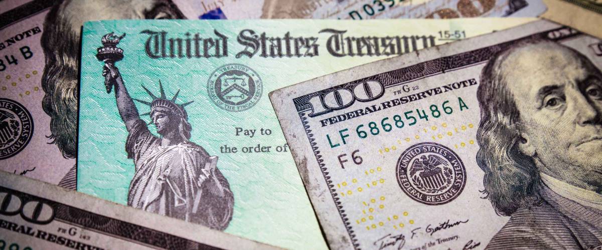 WASHINGTON DC - APRIL 2, 2020: United States Treasury check with US currency. Represents COVID stimulus check.