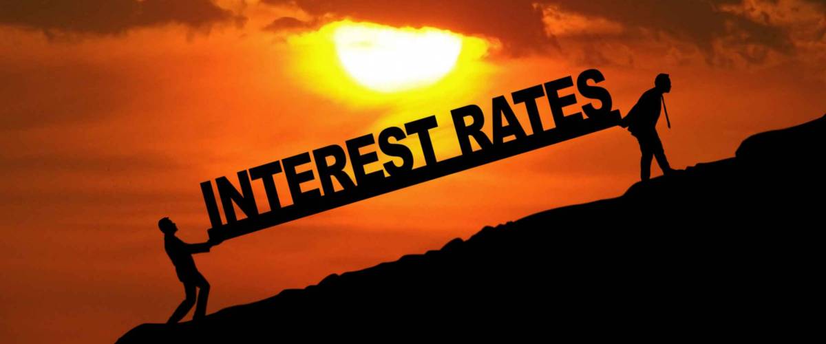 Silhouette of businessmen carrying Interest Rates word uphill