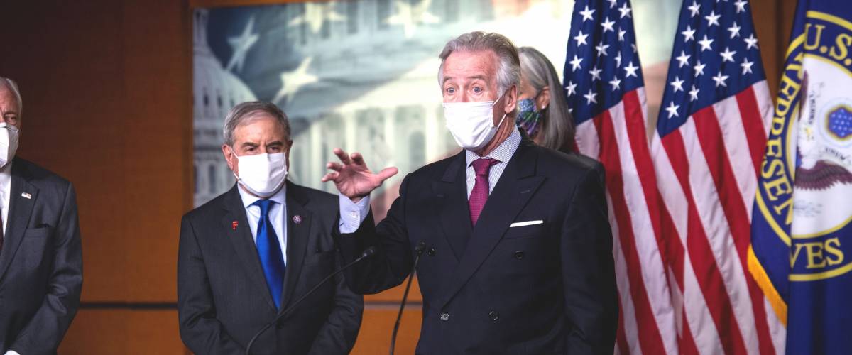 Representative Richard Neal speaks at a podium with a mask on and hand up