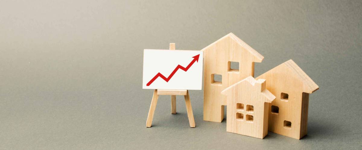 three wooden houses and a red up arrow on the sign. Real estate value increase. High rates of construction, high liquidity. Supply and demand. Rising prices for housing, building maintenance.