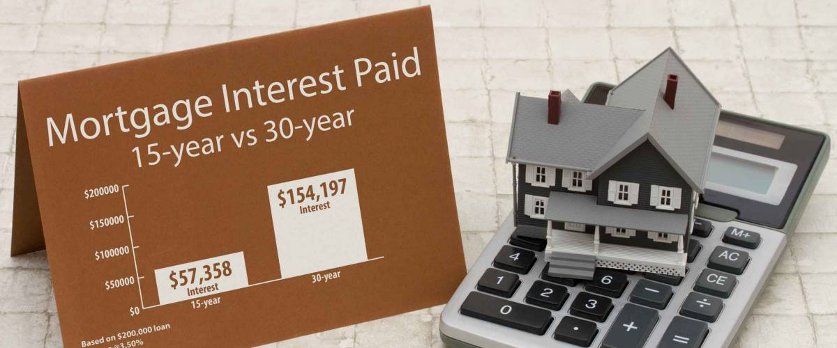 Learning about mortgage interest rates costs, House on a calculator with a card and an infographic on the mortgage interest paid