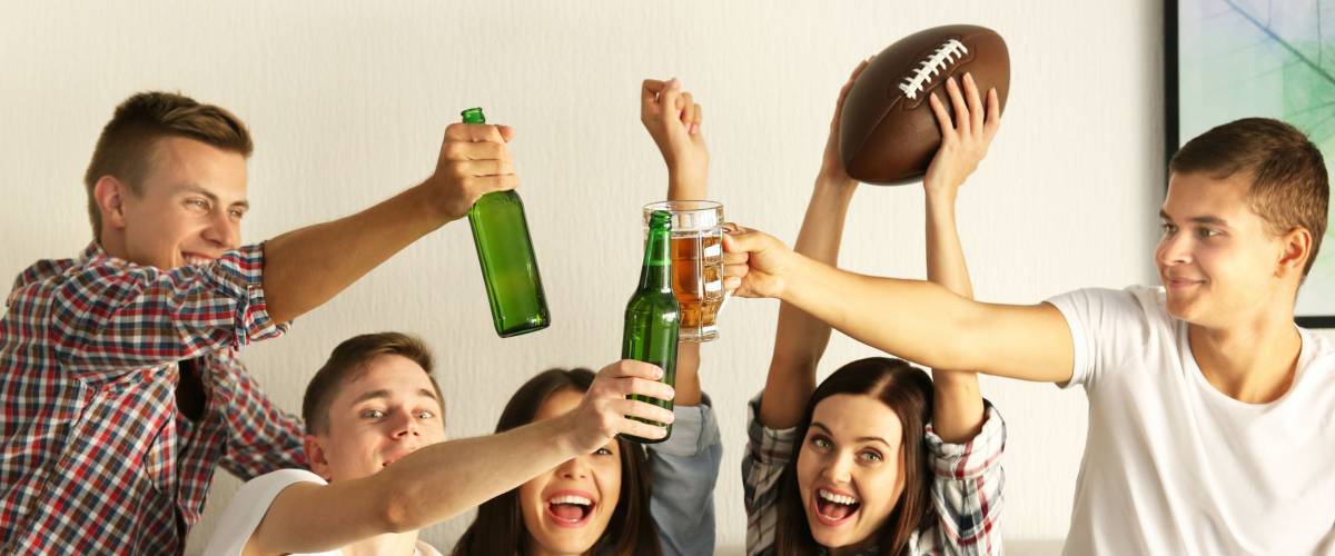 Young fans watching rugby match on TV with beer and snacks