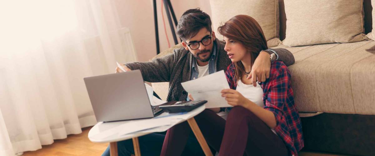 Young married couple doing their paperwork together, paying bills online. Focus on the guy
