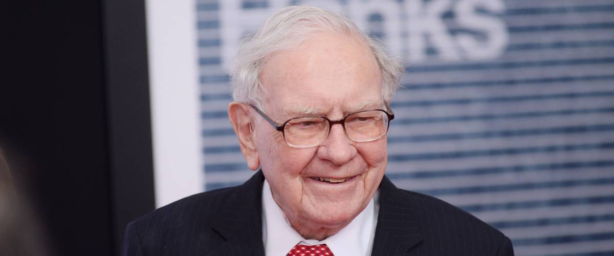 Warren Buffett wearing a suit and smiling at an event