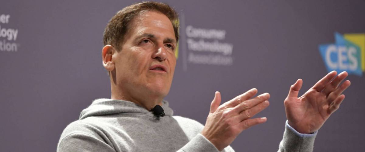 Mark Cuban speaks on a stage with serious look and hands held out, explaining something