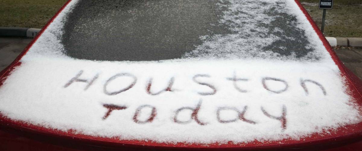 Ice-covered car and an inscription on the snow Houston today