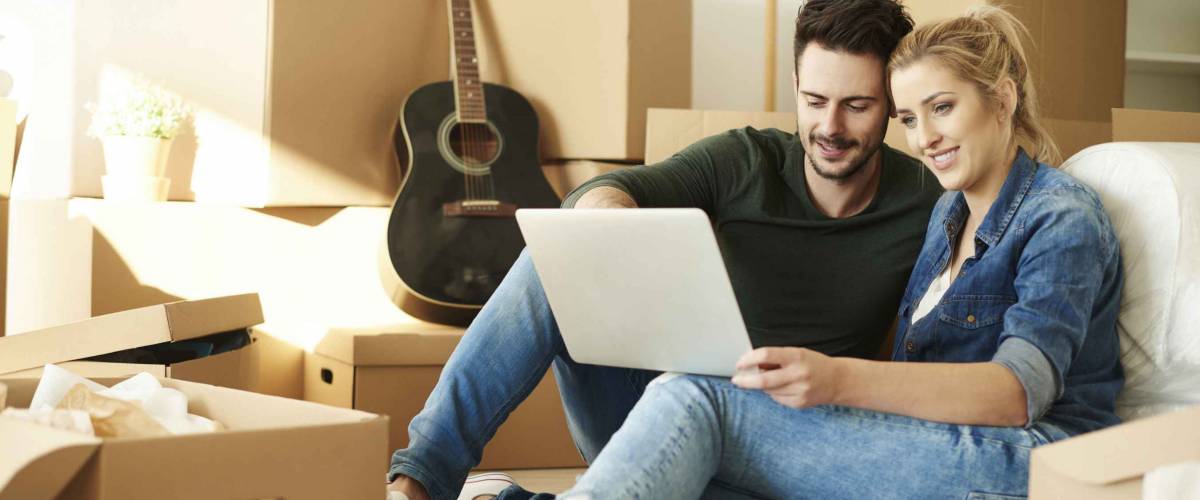 Couple with laptop around cardboard boxes