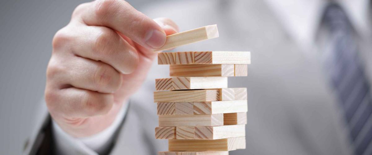 Planning, risk and strategy in business, businessman gambling placing wooden block on a tower