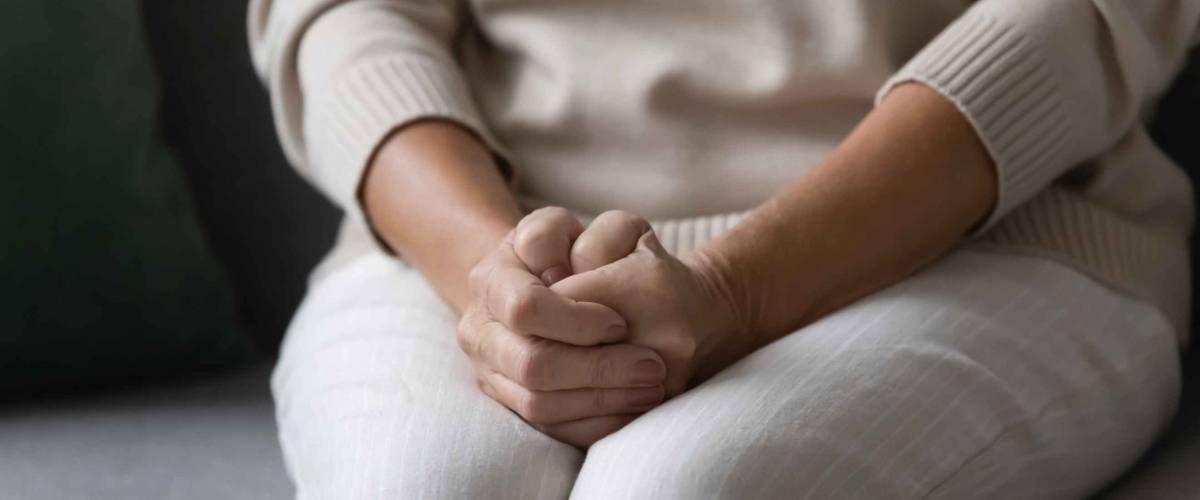 Close up image woman feels nervous anxious or lonely put clenched hands on her lap as she waits for her bonus federal unemployment benefits.