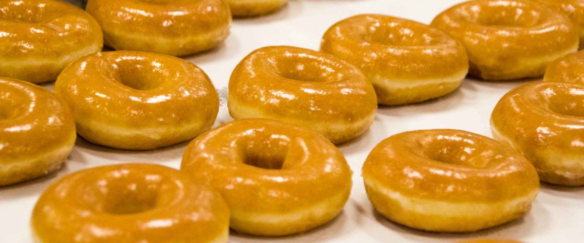 Detail of a doughnut production business with freshly baked donuts coming out of the oven.