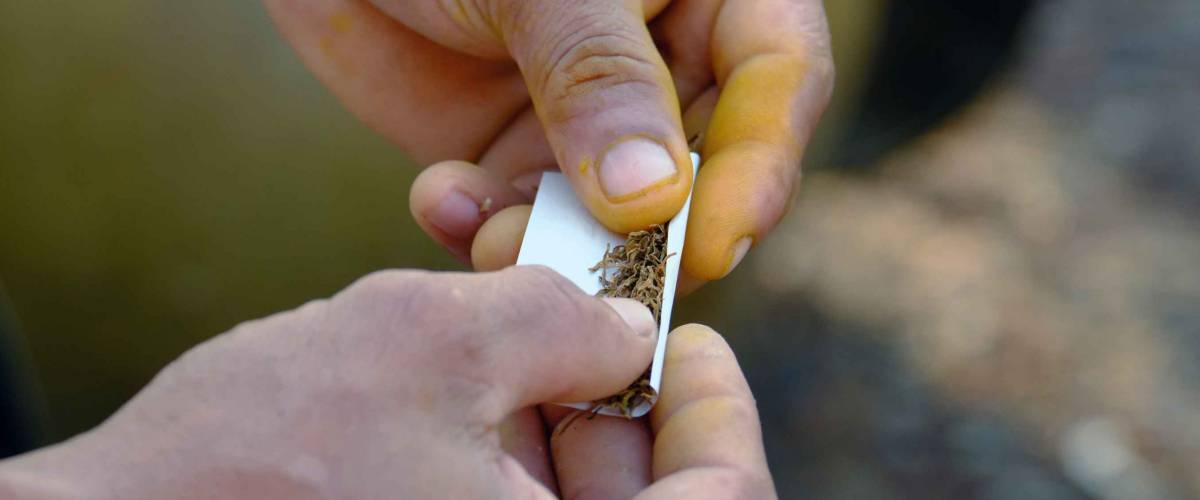 close up of man's hands rolling a cigarette
