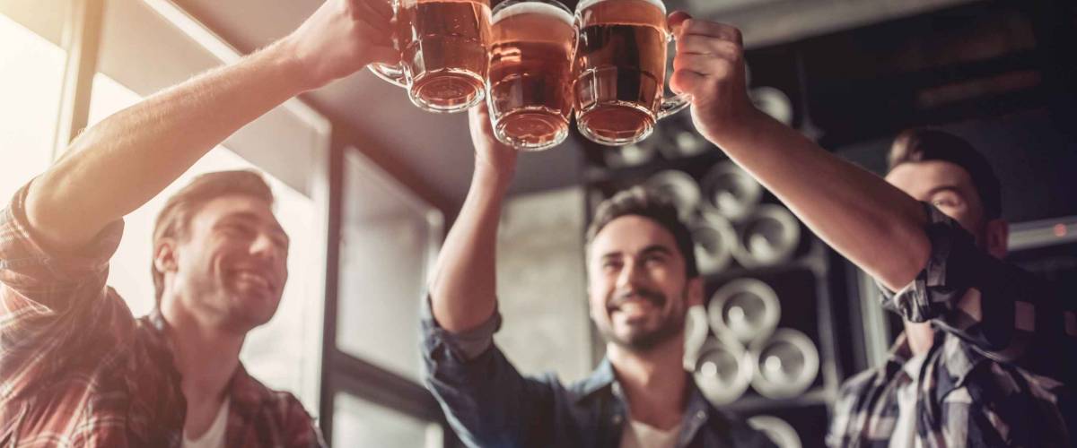 Three men shot from below, clinking beer glasses in the air