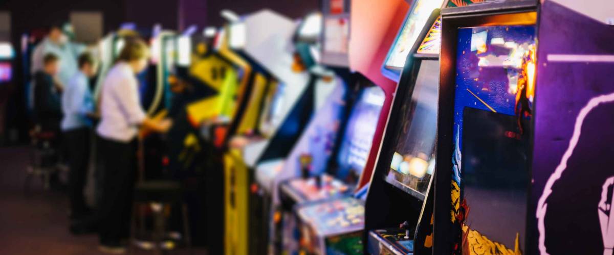 Old Vintage Arcade Games in a dark room and players playing video games in the background