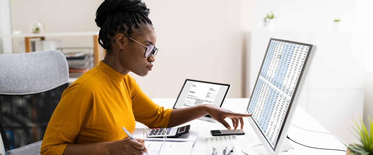 Woman using computer and binder to file her taxes