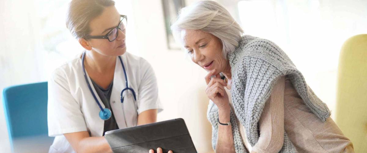 Doctor going through results and medication on tablet with senior patient