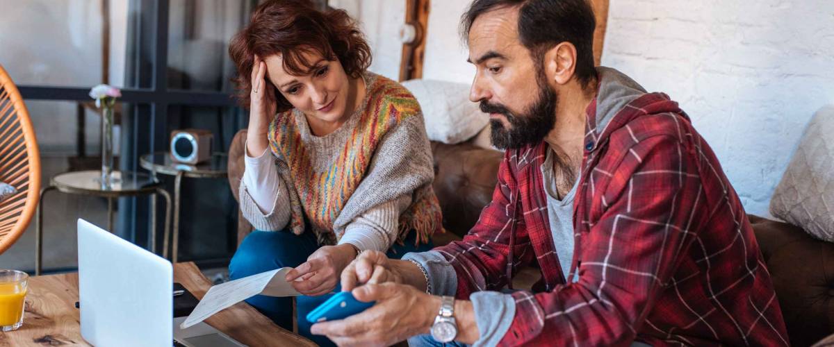 Mature couple sitting at home looking at their finance problems