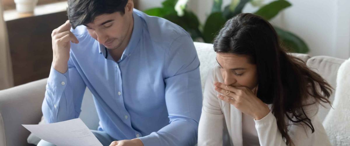Thoughtful pensive young family husband and wife worried about their student loan debt.