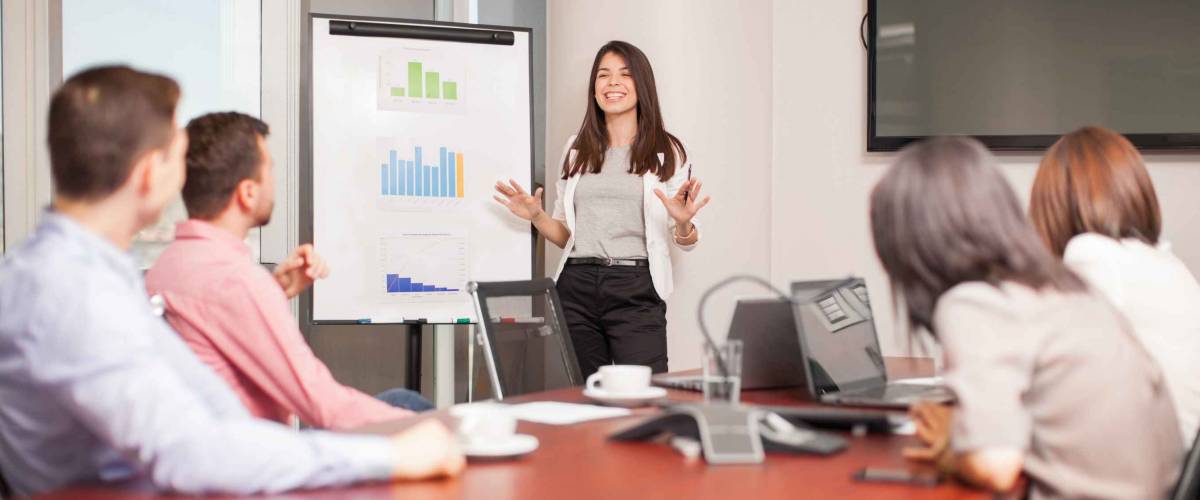 Beautiful young Latin brunette giving a business presentation to some of her clients in a meeting room