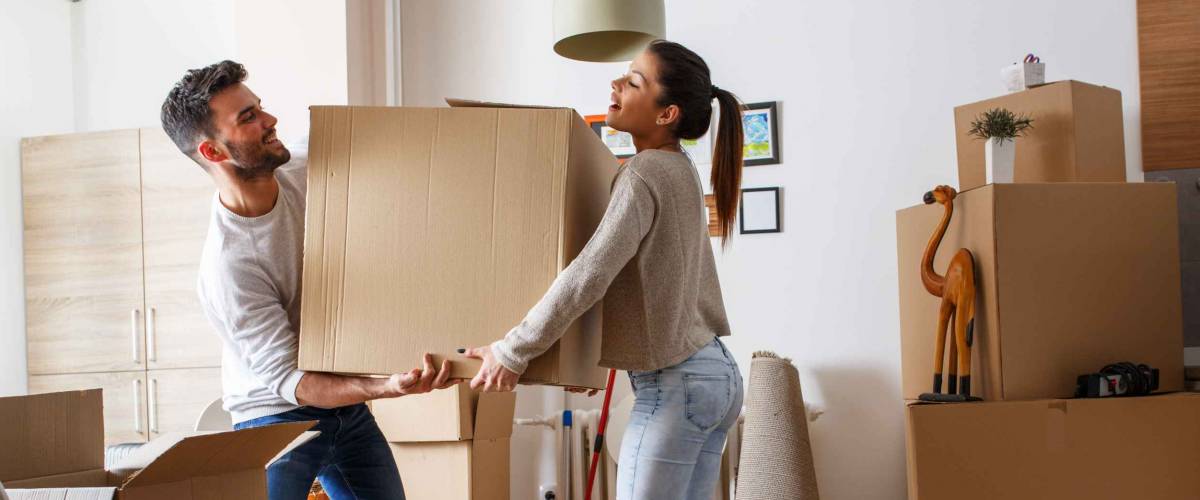 Young couple carrying big cardboard box at new home.Moving house.
